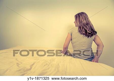 Stock Photography - Young woman sitting on her bed. Fotosearch