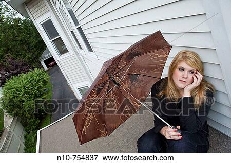 Young woman sitting on her roof, holding an umbrella. View Large Photo Image Stock Photo - Young woman sitting on her roof, holding an umbrella.. Fotosearch