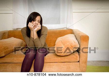 Young woman sitting on her sofa. View Large Photo Image Picture - Young woman sitting on her sofa.. Fotosearch