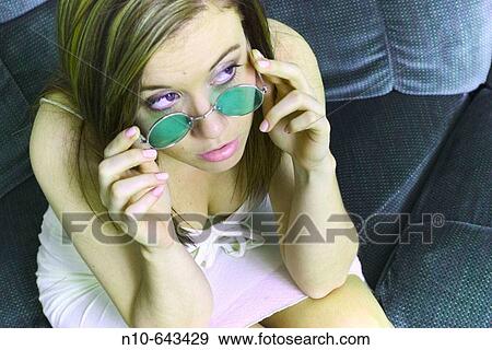 Young woman sitting on her sofa, wearing sunglasses. View Large Photo Image Stock Photo - Young woman sitting on her sofa, wearing sunglasses.. Fotosearch