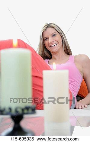 Stock Photography - Young woman sitting on sofa laughing. Fotosearch