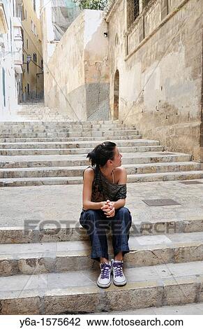 Stock Image - Young woman sitting on stairs. Fotosearch