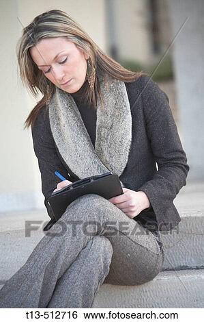Young woman sitting on steps and taking notes View Large Photo Image Stock Photograph - Young woman sitting on steps and taking notes. Fotosearch