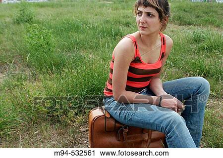 Young woman sitting on suitcase in lot View Large Photo Image Stock Image - Young woman sitting on suitcase in lot. Fotosearch