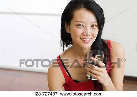 Young woman sitting on water, holding glass of water, smiling View Large Photo Image Stock Photo - Young woman sitting on water, holding glass of water, smiling. Fotosearch
