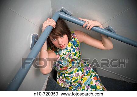 Young woman sitting under the handrail in the hallway of her apartment building. View Large Photo Image Stock Photo - Young woman sitting under the handrail in the hallway of her apartment building.. Fotosearch