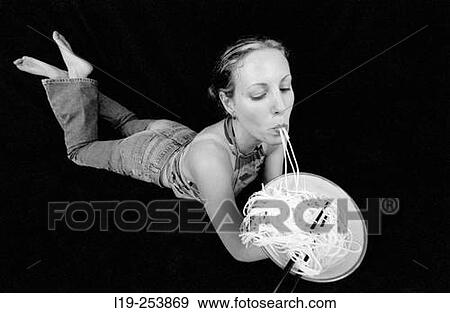 Stock Photo - Young woman slurping noodles.. Fotosearch