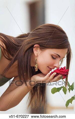 Young woman smelling a flower View Large Photo Image Stock Photo - Young woman smelling a flower. Fotosearch
