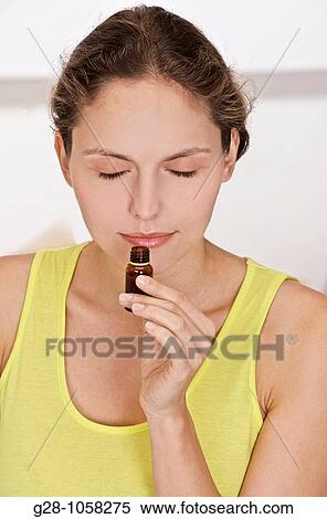 young woman smelling a small bottle of essential oil View Large Photo Image Stock Photography - young woman smelling a small bottle of essential oil. Fotosearch