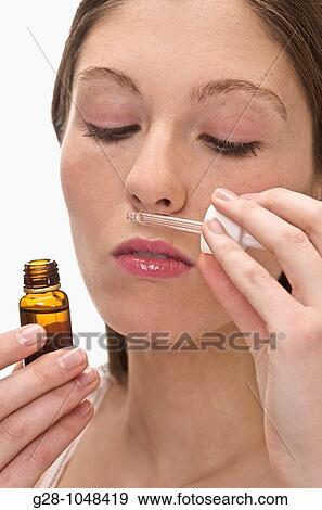 Stock Photo - young woman smelling essential oil, with a small bottle and a dropper. Fotosearch