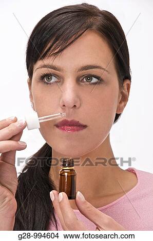 young woman smelling essential oil with a small bottle and a dropper View Large Photo Image Picture - young woman smelling essential oil with a small bottle and a dropper. Fotosearch