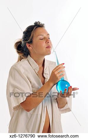 Stock Image - Young woman smelling perfume blue. Fotosearch