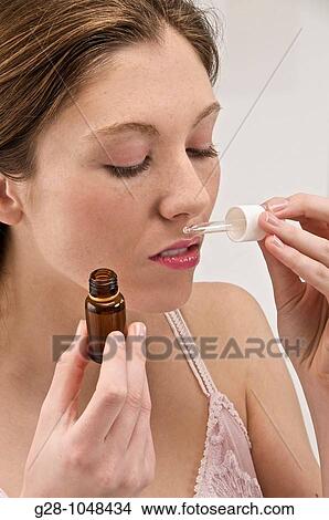 young woman smelling with pleasure essential oil with a dropper View Large Photo Image Picture - young woman smelling with pleasure essential oil with a dropper. Fotosearch
