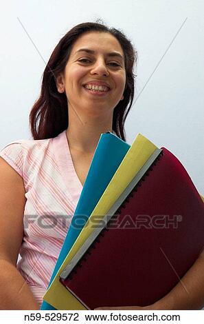 Stock Image - Young woman smiling with work files.. Fotosearch