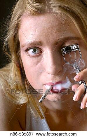 Young woman smoking and curling eyelashes View Large Photo Image Stock Photo - Young woman smoking and curling eyelashes. Fotosearch
