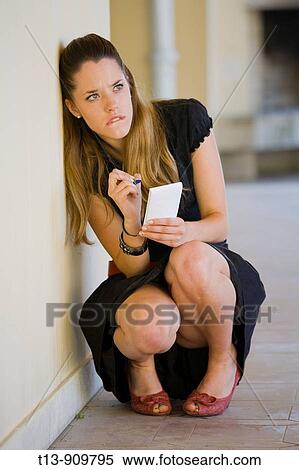 Young woman squatting with paper and pencil in hands View Large Photo Image Stock Photography - Young woman squatting with paper and pencil in hands. Fotosearch