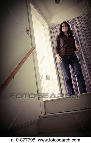 Stock Photography - Young woman standing at the top of a staircase. Model and Property Released.. Fotosearch