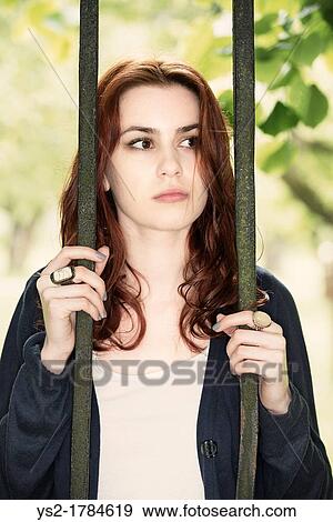 Young woman standing behind the bars of an iron gate View Large Photo Image Stock Photo - Young woman standing behind the bars of an iron gate. Fotosearch
