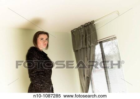 Young woman standing by a window View Large Photo Image Stock Photography - Young woman standing by a window. Fotosearch