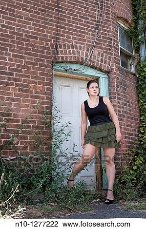 Stock Image - Young woman standing by her apartment door. Fotosearch
