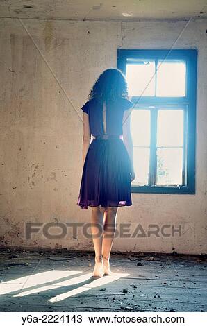 Young woman standing by the window. View Large Photo Image Stock Image - Young woman standing by the window.. Fotosearch