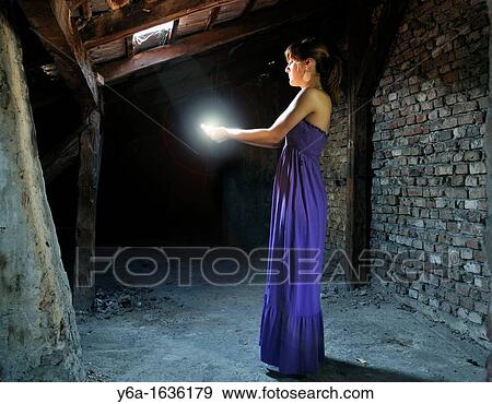 Young woman standing in attic capturing lightbeam between hands View Large Photo Image Stock Photo - Young woman standing in attic capturing lightbeam between hands. Fotosearch