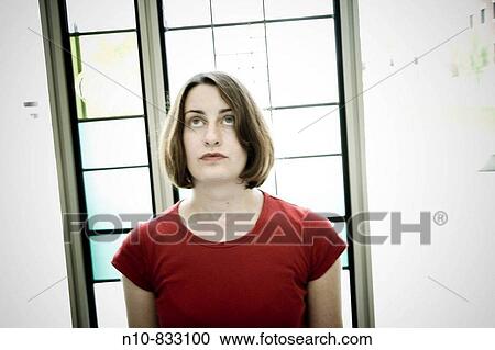 Young woman standing in front of a window. View Large Photo Image Stock Image - Young woman standing in front of a window.. Fotosearch