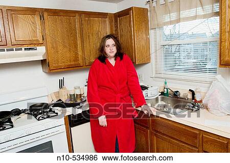 Young woman standing in her kitchen View Large Photo Image Stock Photograph - Young woman standing in her kitchen. Fotosearch