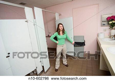 Young woman standing in the doorway of a stall in a women's bathroom. View Large Photo Image Stock Photograph - Young woman standing in the doorway of a stall in a women's bathroom.. Fotosearch