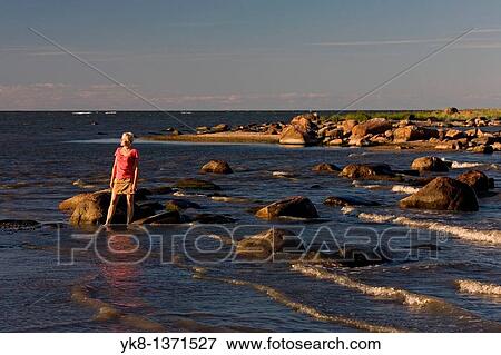 Stock Photo - Young Woman Standing in Water by Baltic Sea Coast. Fotosearch