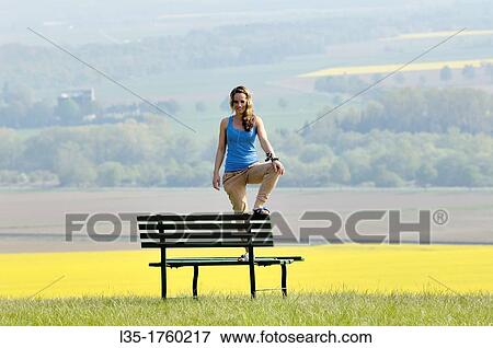 Young woman standing on bench View Large Photo Image Stock Photo - Young woman standing on bench. Fotosearch