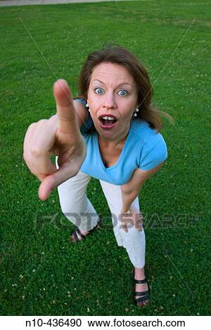 Young woman, standing on the grass at a park, dramatically pointing with her finger. View Large Photo Image Stock Image - Young woman, standing on the grass at a park, dramatically pointing with her finger.. Fotosearch