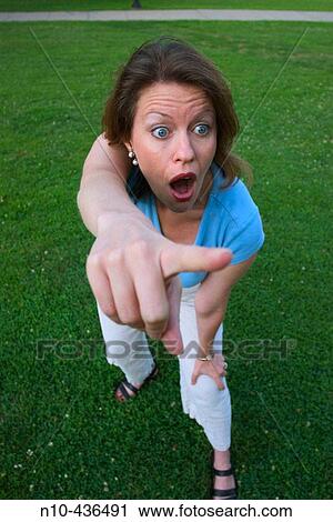 Young woman, standing on the grass at a park, dramatically pointing with her finger. View Large Photo Image Stock Image - Young woman, standing on the grass at a park, dramatically pointing with her finger.. Fotosearch