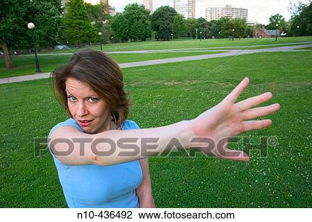 Young woman, standing on the grass at a park, dramatically waving her hand. View Large Photo Image Stock Image - Young woman, standing on the grass at a park, dramatically waving her hand.. Fotosearch