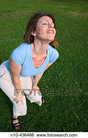 Young woman, standing on the grass at a park, dramatically expressing herself. View Large Photo Image Stock Photo - Young woman, standing on the grass at a park, dramatically expressing herself.. Fotosearch