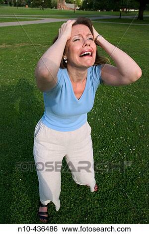 Stock Photograph - Young woman, standing on the grass at a park, dramatically gesturing.. Fotosearch