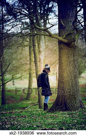 Stock Photograph - Young woman staring at the light in Richmond Park wood, London, UK. Fotosearch