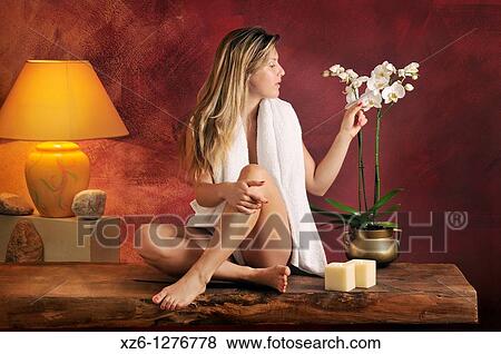 Stock Photo - Young woman stroking an orchid in relaxation area. Fotosearch