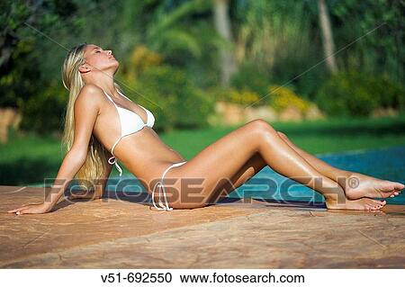 Young woman sunbathing by a pool View Large Photo Image Stock Image - Young woman sunbathing by a pool. Fotosearch