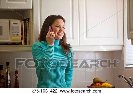 young woman talking on cell phone in kitchen View Large Photo Image Stock Image - young woman talking on cell phone in kitchen. Fotosearch