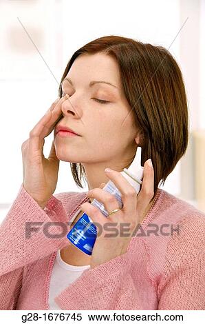 Stock Photography - Young woman using a sea water nose spray. Fotosearch