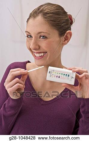 Stock Photo - young woman using a self urine test to detect her level of sugar for diabetes. Fotosearch