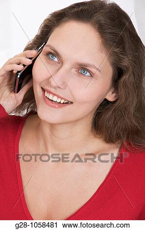 Stock Image - young woman using her Iphone and smiling. Fotosearch