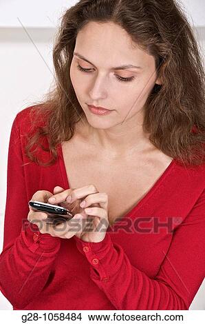 Picture - young woman using her Iphone to send or read information. Fotosearch