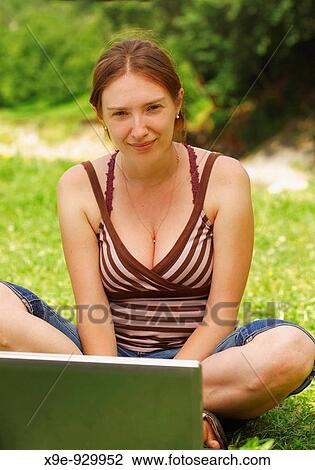 Stock Image - Young woman using her laptop outdoors. Fotosearch
