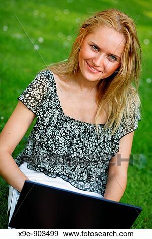 Stock Photo - Young woman using her laptop outdoors. Fotosearch