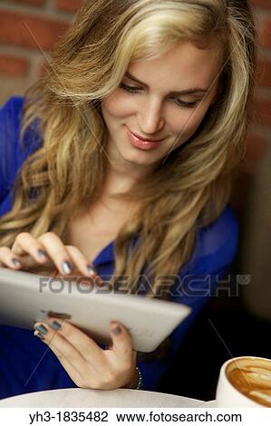 Young woman using ipad at a cafe View Large Photo Image Stock Image - Young woman using ipad at a cafe. Fotosearch
