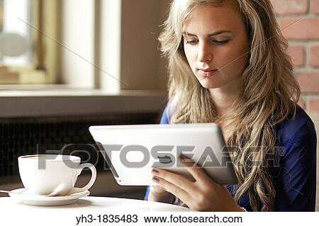 Young woman using ipad at a cafe View Large Photo Image Stock Image - Young woman using ipad at a cafe. Fotosearch