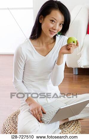 Young woman using laptop and eating apple, close-up View Large Photo Image Stock Image - Young woman using laptop and eating apple, close-up. Fotosearch