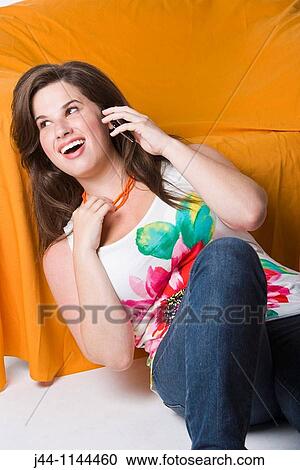 Young woman using mobile phone leaning on sofa smiling View Large Photo Image Stock Image - Young woman using mobile phone leaning on sofa smiling. Fotosearch